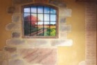 Revestimiento de entrada de vivienda. Tematización en imitaciones piedra y ladrillo, aprovechamos ventana antigua para decoración.
